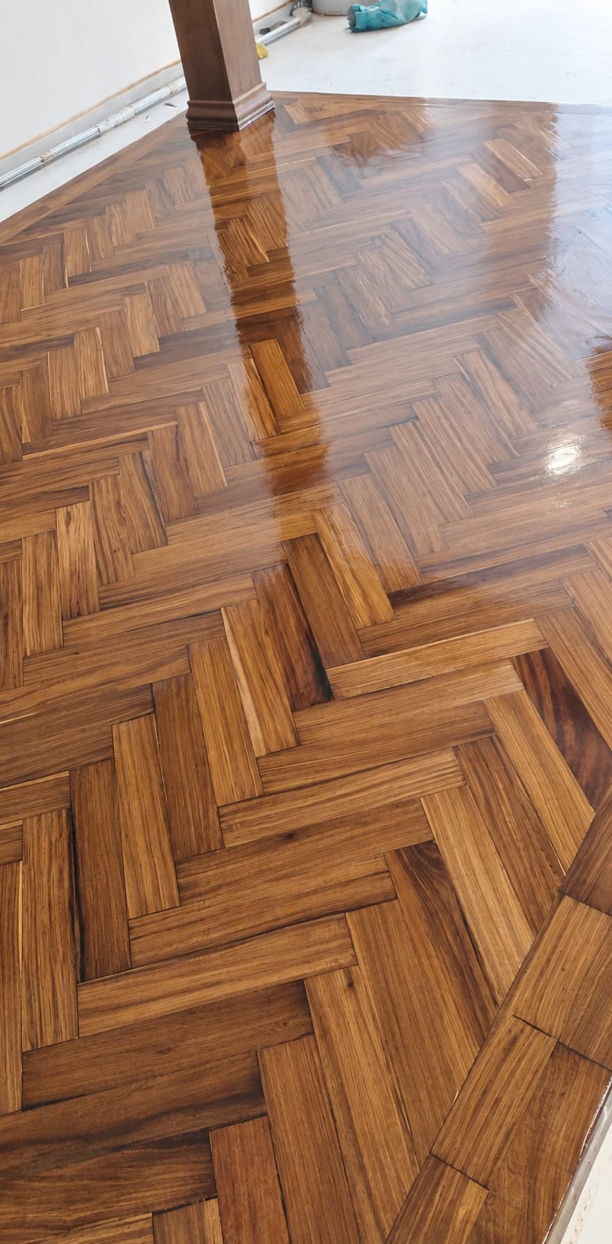 Vue rapprochée du parquet brun à bâtons rompus et de ses variations de grain. Version retouchée par IA.