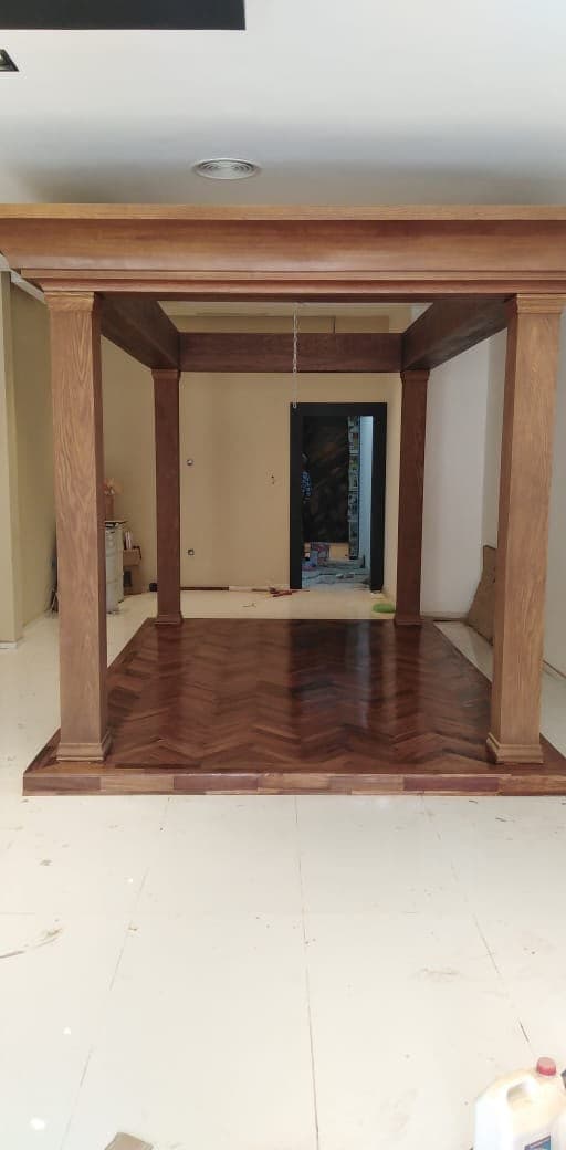 Parquet à bâtons rompus brun, encadré par une structure de colonnes en bois.