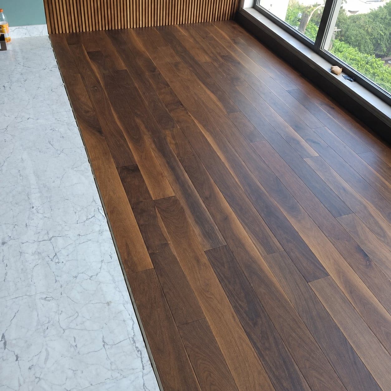 Parquet brun près de la baie et du mur à tasseaux, version retouchée par IA.