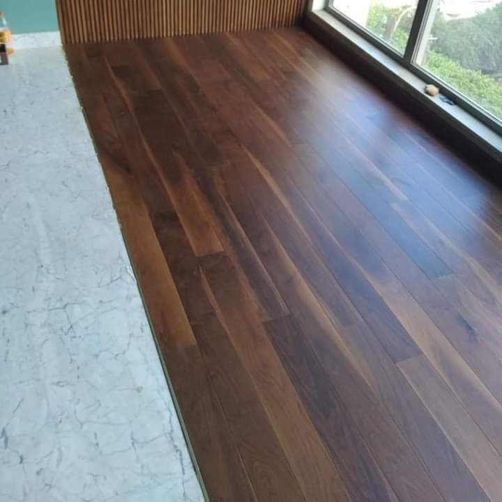 Parquet en lames brunes près d’une fenêtre et d’une paroi de tasseaux.